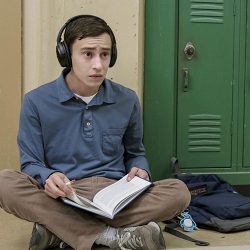 Atypical lead actor sitting against green lockers