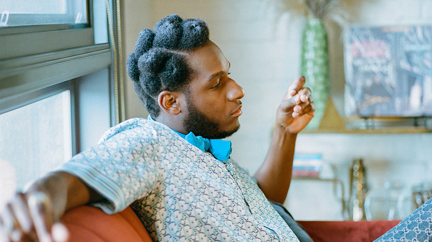 Leon Bridges posing on couch listening to music