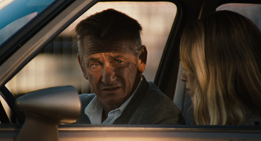 Sean Penn and Dylan Penn sitting in a car, looking at each other, in a scene from the movie Flag Day.