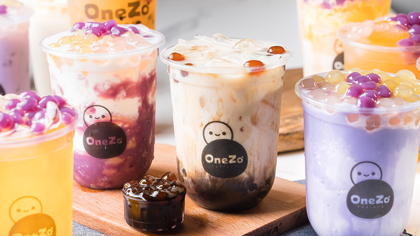 Multiple cups of colourful bubble teas and a small bowl of tapioca pearls.