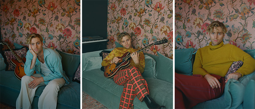 Three photos of Luke Hemmings in various seated positions on a soft teal sofa against a floral wallpapered wall — resting his head on his fist, playing the guitar, and posed with his arm on the armrest.