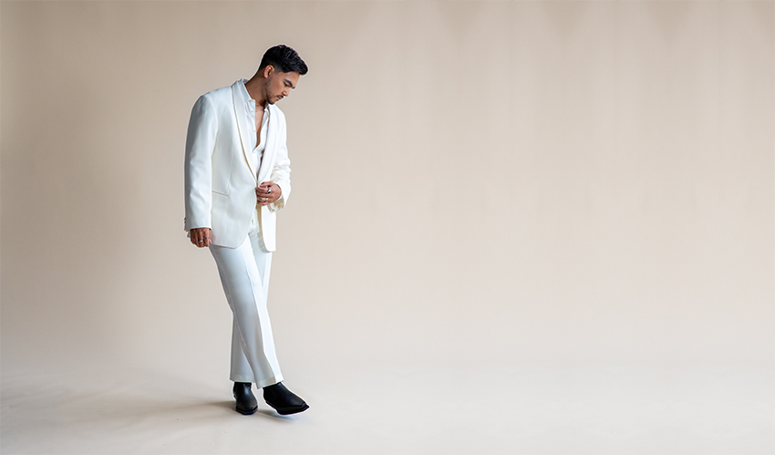 Tyler Shaw dressed in an all-white suit, standing against a neutral backdrop.
