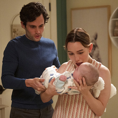 Scene from You with Penn Badgley and Victoria Pedretti holding a baby.