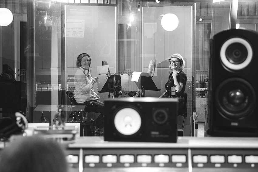 Black and white photo of Agnetha Fältskog and Frida Lyngstad of ABBA sitting inside the recording studio.