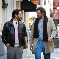 Paul Rudd and Will Ferrell looking at each other, talking, while walking down the street.