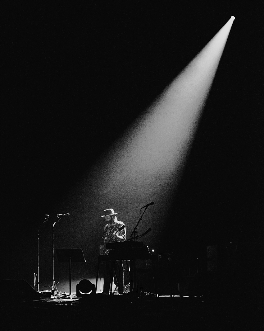 Black and white photo of Dallas Green performing onstage with one spotlight shining down on him.