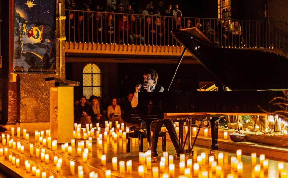Man sitting at piano surrounded by candles